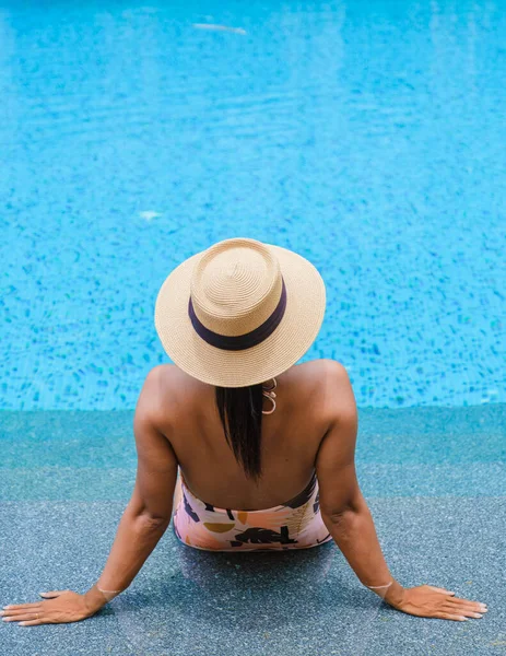 Asian women with hat relaxing in swimming pool, women swimming pool banner holiday vacation concept, Asian women in blue swimming pool luxury vacation