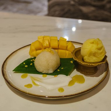 Sticky rice with mango and ice cream on a plate. dinner with a sweet dessert 