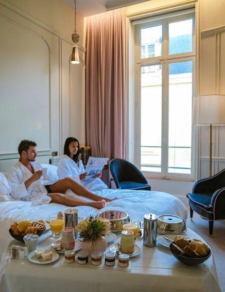 Morning wake up in bed in Paris with breakfast coffee and a newspaper, Selective focus of a couple in bed men and woman honeymoon valentine couple in a hotel in Paris