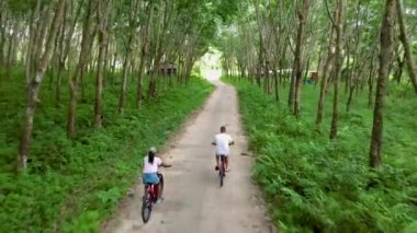 A couple of men and women on a bicycle at a rubber plantation in Thailand. 