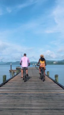 Tayland 'da Phuket yakınlarında bir tropikal adada bisiklete binen iki erkek ve bir kadın, Naka Adası' ndaki bir rıhtımda iki erkek ve bir kadın bisikleti.. 