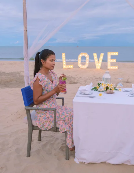 Romantic dinner on the beach of Huahin Thailand, dinner by candle light in Hua Hin , Valentines concept. Asian women having dinner on the beach during sunset