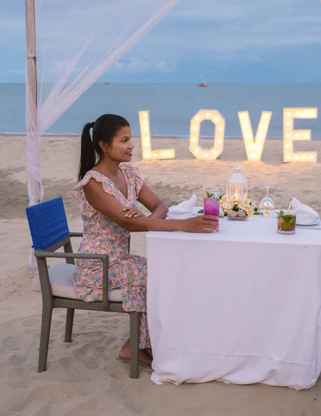 Romantic dinner on the beach of Huahin Thailand, dinner by candle light in Hua Hin , Valentines concept. Asian women having dinner on the beach during sunset