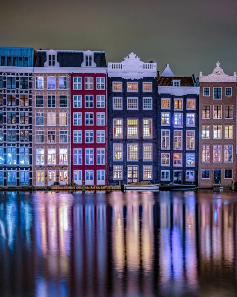 Amsterdam at night with dancing colorful house at the Amsterdam canals in the Netherlands.