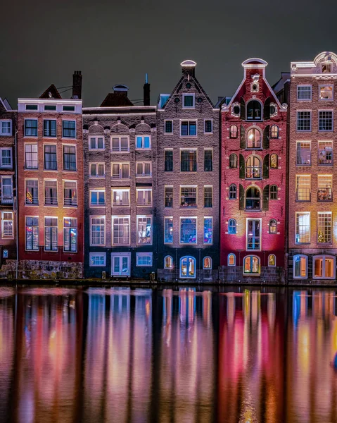 Amsterdam at night with dancing colorful house at the Amsterdam canals in the Netherlands.