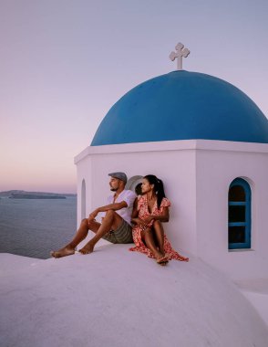 Santorini Yunanistan 'da tatilde, iki erkek ve kadın beyaz boyalı binalarla Oia Santorini' yi ziyaret ediyorlar. Santorini Yunanistan 'da güneşin doğuşunu izleyen genç çift