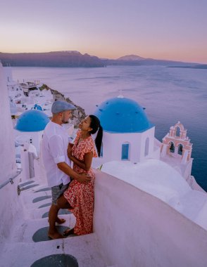 Santorini Yunanistan 'da tatilde, iki erkek ve kadın beyaz boyalı binalarla Oia Santorini' yi ziyaret ediyorlar. Santorini Yunanistan 'da güneşin doğuşunu izleyen genç çift