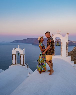 Santorini Yunanistan 'da tatilde, iki erkek ve kadın beyaz boyalı binalarla Oia Santorini' yi ziyaret ediyorlar. Santorini Yunanistan 'da güneşin doğuşunu izleyen genç çift