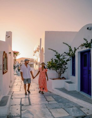 Santorini Yunanistan 'da tatilde, iki erkek ve kadın beyaz boyalı binalarla Oia Santorini' yi ziyaret ediyorlar. Santorini Yunanistan 'da güneşin doğuşunu izleyen genç çift