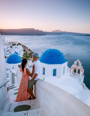 Santorini Yunanistan 'da tatilde, iki erkek ve kadın beyaz boyalı binalarla Oia Santorini' yi ziyaret ediyorlar. Santorini Yunanistan 'da güneşin doğuşunu izleyen genç çift