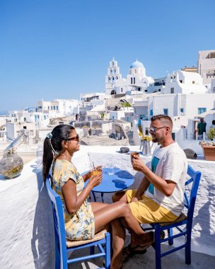 Santorini Yunanistan 'da tatilde, iki erkek ve kadın beyaz boyalı binalarla Oia Santorini' yi ziyaret ediyorlar. Santorini Yunanistan 'da güneşin doğuşunu izleyen genç çift