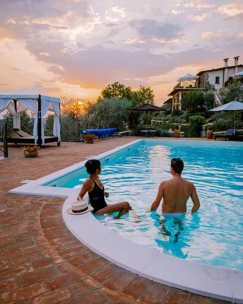 Luxury country house with swimming pool in Italy. Pool and old farmhouse during sunset in central Italy. couple man and woman mid age on vacation in Italy enjoying the swimming pool during sunset