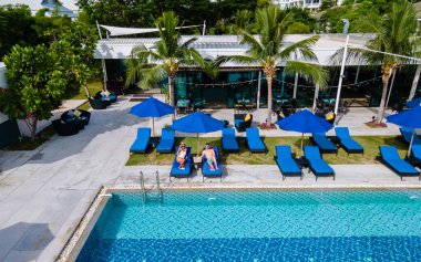 Havuzun yukarısından hava manzarası, yukarıdan drone ile tropikal yüzme havuzu. Erkekler ve kadınlar balayı sırasında lüks bir havuzda dinleniyorlar.