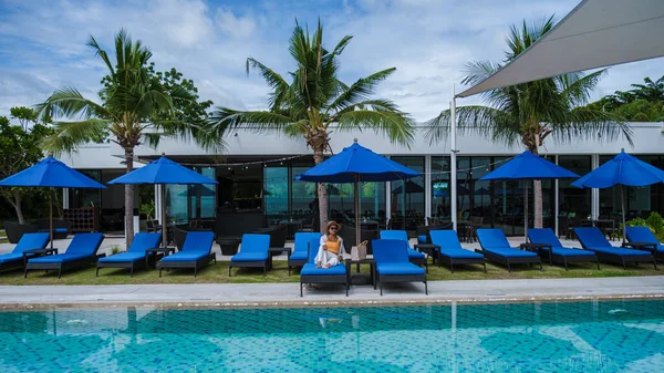 Asyalı kadınlar havuz kenarında güneşleniyorlar, kadınlar balayı sırasında lüks bir havuzda dinleniyorlar.