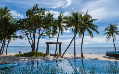 Hua Hin Tayland, Huahin 'de lüks bir tatil köyünde palmiye ağaçları olan tropikal bir havuz, okyanusa bakan palmiye ağaçları olan bir havuz.