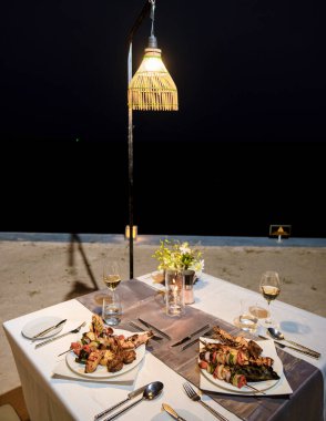 Okyanus kenarındaki lüks yemek masasında ıstakoz, balık ve Tayland yemekleri.. 