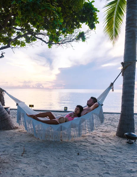 Couple of men and women watching the sunrise in a hammock on a tropical beach in Hua Hin Thailand. Asian women and European men in a hammock on the beach of Huahin Thailand