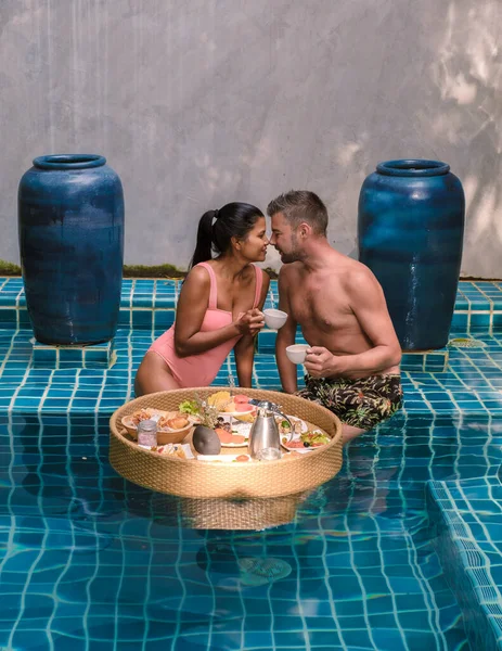 プールで朝食をとるカップル プールで朝食をとるアジア系女性と白人男性 — ストック写真