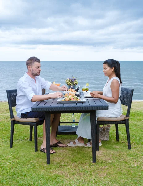 夕方にはビーチでロマンチックなディナーを楽しんでいる男女のカップル アジア系の女性と白人男性がフアイン タイのビーチで夕食をとる — ストック写真