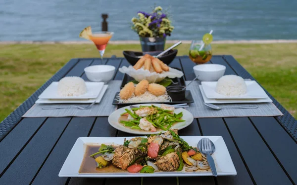 Luxury dinner table by the ocean with lobster, fish, and Thai food.