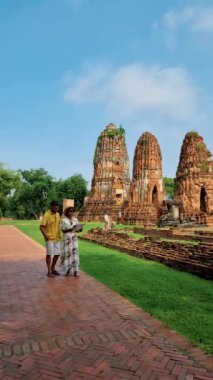 Ayutthaya, Tayland Wat Mahathat 'da, şapkalı ve turist haritalı bir çift adam ve kadın Ayutthaya' daki eski bir Pagoda 'ya bakıyorlar.