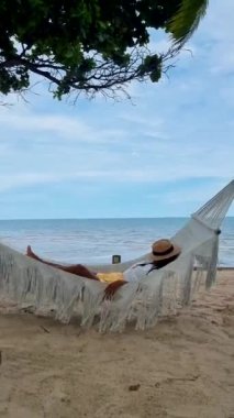 Hua Hin Tayland 'da bir hamakta güneşin doğuşunu izleyen kadınlar. Huahin Tayland sahilindeki hamakta yaşayan Asyalı kadınlar.