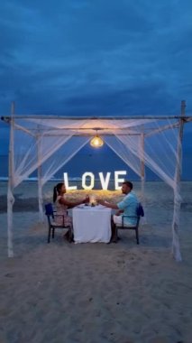 Huahin Tayland sahilinde romantik bir akşam yemeği Hua Hin 'de mum ışığında akşam yemeği, sevgililer günü konsepti. Tayland sahilinde romantik bir akşam yemeği yiyen iki erkek ve kadın. 