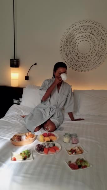 アジアの女性はベッドで朝食をとり 寝室の女性は朝に朝食をとる コーヒーとフルーツで — ストック動画