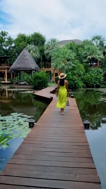 아시아 여성들은 아시아의 휴양지에 나무로 부두를 연못에 나무로 부두에서 모자를 — 비디오