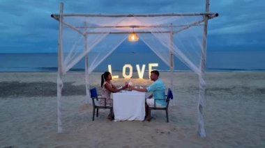 Huahin Tayland sahilinde romantik bir akşam yemeği Hua Hin 'de mum ışığında akşam yemeği, sevgililer günü konsepti. Tayland sahilinde romantik bir akşam yemeği yiyen iki erkek ve kadın. 