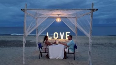 Huahin Tayland sahilinde romantik bir akşam yemeği Hua Hin 'de mum ışığında akşam yemeği, sevgililer günü konsepti. Tayland sahilinde romantik bir akşam yemeği yiyen iki erkek ve kadın. 