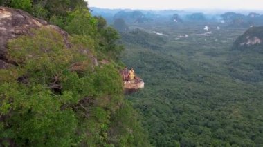 Ejderha Tepesi dağı Krabi Tayland, genç bir gezgin uçurumun üzerindeki kayanın üzerinde oturuyor, güzel bir manzarası var. Tayland, Krabi 'deki Khao Ngon Nak Doğa Yolu' nda Ejder Tepesi veya Khuan Sai.
