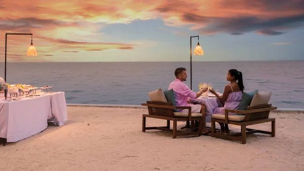 남녀가 저녁에 해변에서 로맨틱 식사를 있습니다 아시아 여자들 코카서스 남자들 — 스톡 사진