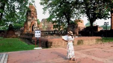 Ayutthaya, Tayland Wat Mahathat 'da, şapkalı ve turist haritalı kadınlar Ayutthaya' daki eski bir Pagoda 'ya bakıyorlar.