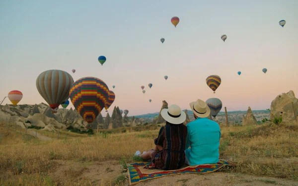 カパドキヤ カッパドキア トルコ 休暇中にカパドキヤ カッパドキア トルコの熱気球を見ている日の出の間に幸せな若いカップル — ストック写真
