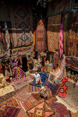 Kapadokya 'daki mağara evi Kapadokya' daki eski bir Türk halı dükkanında genç bir turist. Goreme 'deki renkli halı dükkanı