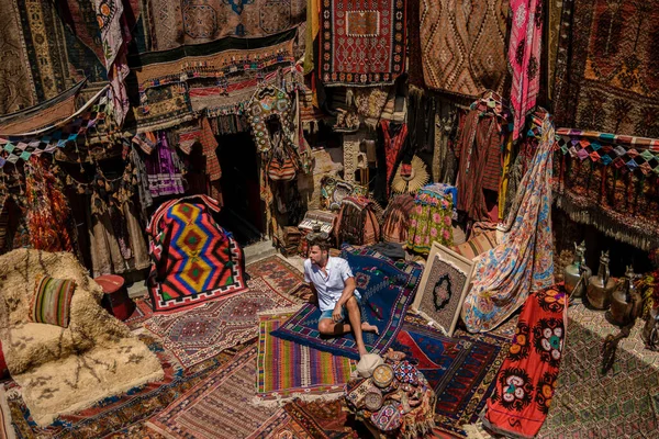 young man tourist at an old traditional Turkish carpet shop in cave house Cappadocia, Turkey Kapadokya. Colorful carpet shop in Goreme