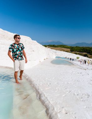 Pamukkale 'deki doğal travertin havuzları ve terasları. Türkiye 'nin güneybatısındaki pamuk kale, Pamukkale Türkiye' deki doğal havuzda gün batımını izleyen gençler