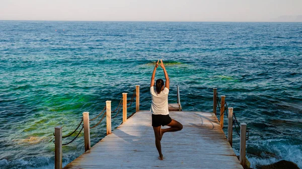 Frauen Praktizieren Yoga Auf Einem Holzsteg Meer Während Des Sonnenuntergangs — Stockfoto