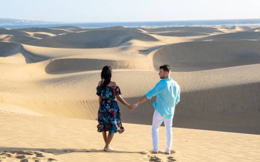 Maspalomas sahilinde yürüyen çift Gran Canaria İspanya, Maspalomas Gran Canaria 'nın kum tepelerindeki kadın ve erkekler