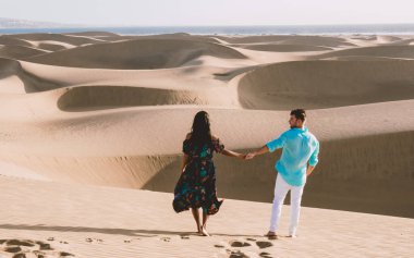 Maspalomas sahilinde yürüyen bir çift Gran Canaria İspanya 'da tatil sırasında Maspalomas Gran Canaria' nın kum tepeleri çölünde yürüyen erkek ve kadın.