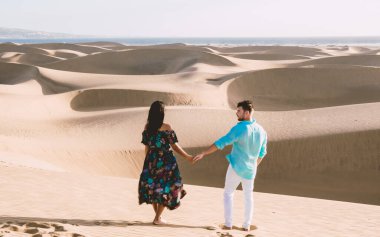 Maspalomas sahilinde yürüyen bir çift Gran Canaria İspanya 'da tatil sırasında Maspalomas Gran Canaria' nın kum tepeleri çölünde yürüyen erkek ve kadın.