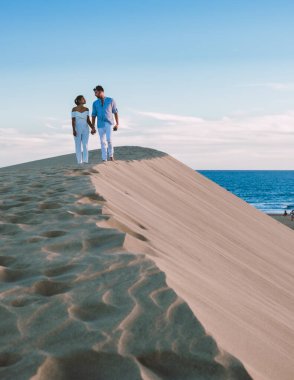 Maspalomas sahilinde yürüyen bir çift Gran Canaria İspanya 'da tatil sırasında Maspalomas Gran Canaria' nın kum tepeleri çölünde yürüyen erkek ve kadın.