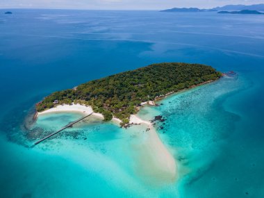 Kristal berraklığında okyanusu olan tropik bir ada, Koh Kham Trat Tayland, Koh Mak Tayland yakınlarındaki tropik adanın havadan görünüşü. Beyaz kumlu sahil, palmiye ağaçları ve okyanusta büyük siyah kaya taşları.