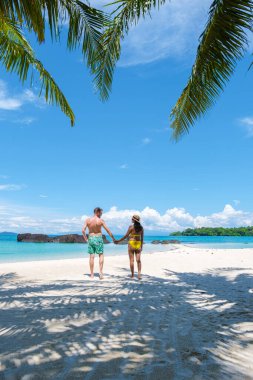 Koh Mak Tayland yakınlarındaki Koh Kham Trat adasında, Tayland 'da tropik bir plajda yürüyen bir çift. Koh Kham Adası 'nda palmiye ağaçları olan beyaz kumlu plaj.