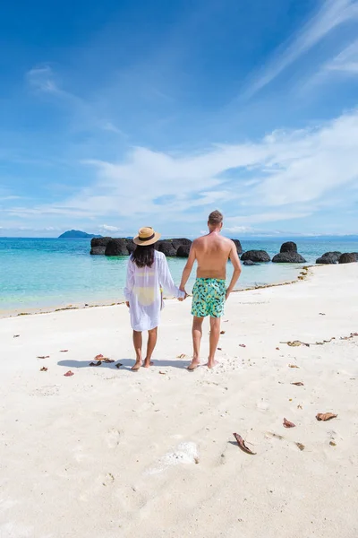 在泰国的一个白色热带海滩上 穿着泳裤的男男女女正在散步 男子游泳短小 亚洲女子在沙滩上 手握棕榈树和白沙滩 — 图库照片
