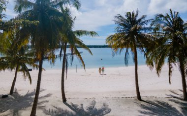 Tayland 'da tropik bir plajda, Koh Kham Trat' ta Koh Mak yakınlarında insansız hava aracı görüntüsü. Bir çift Asyalı kadın ve tropikal bir plajda beyaz erkek.