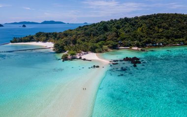 Tayland 'da tropik bir plajda, Koh Kham Trat' ta Koh Mak yakınlarında insansız hava aracı görüntüsü. Bir çift Asyalı kadın ve tropikal bir plajda beyaz erkek.