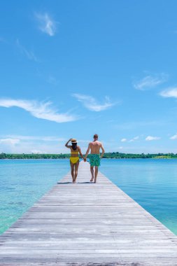 Tayland 'da tropik bir adada tahta bir tahtanın üzerinde yürüyen çift, Koh Mak Trat yakınlarındaki Koh Kham, tropik bir adada tahta bir iskele.