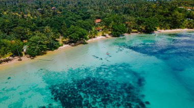 Erkekler ve kadınlar Koh Mak Tayland 'ın tropikal adasının okyanusunda Kayak' ta. Erkekler ve kadınlar mavi bir okyanusta kano ve palmiye ağaçlı beyaz plajda